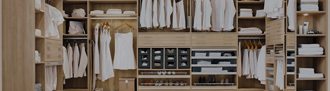 Ein geräumiger, moderner begehbarer Kleiderschrank mit einem großen Spiegel, der stilvolle Kleidung und Accessoires reflektiert.