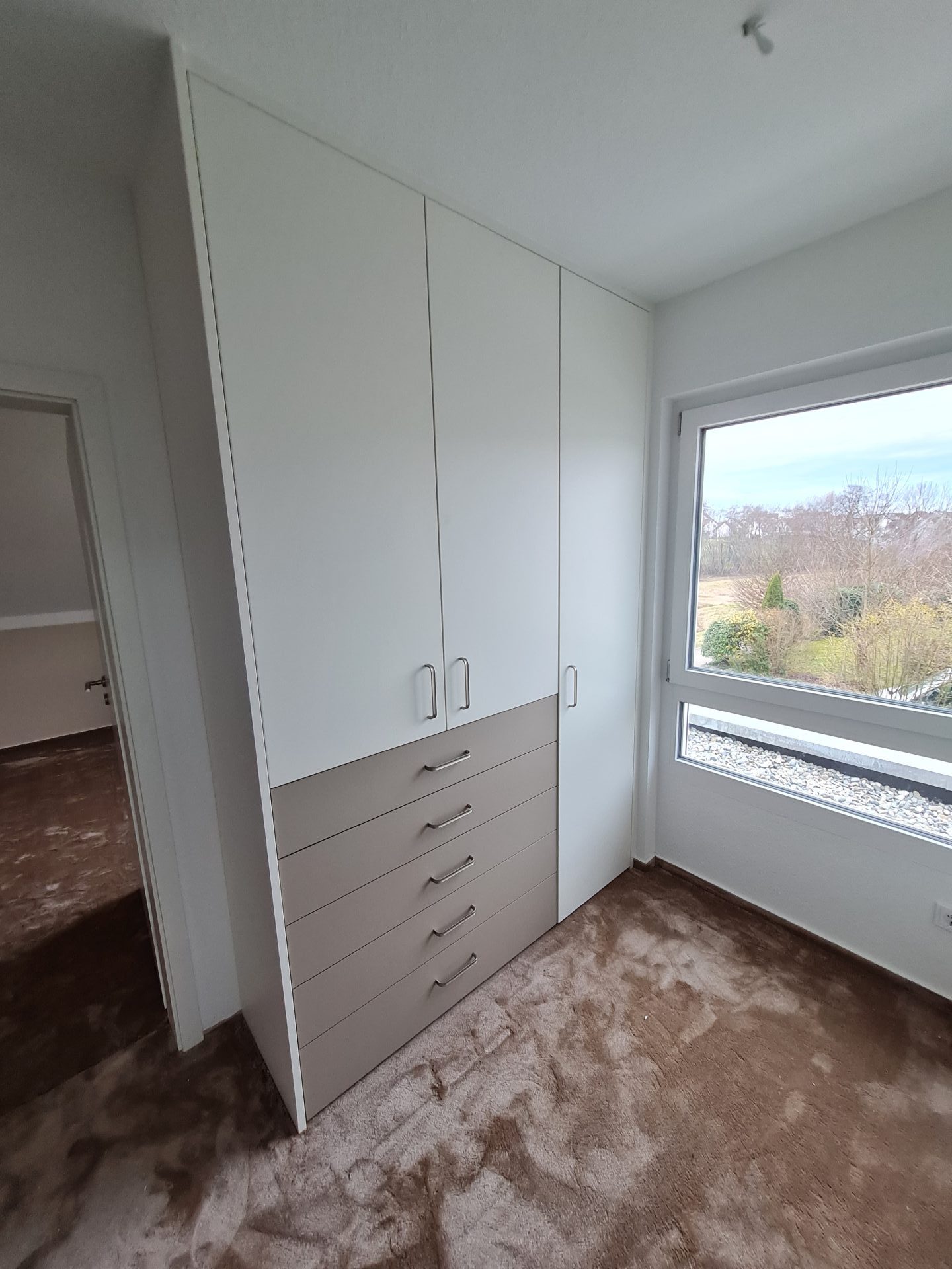 Ein eleganter Kleiderschrank mit Schiebetüren steht vor einem warmen Holzboden und unterstreicht so das moderne Interieur.