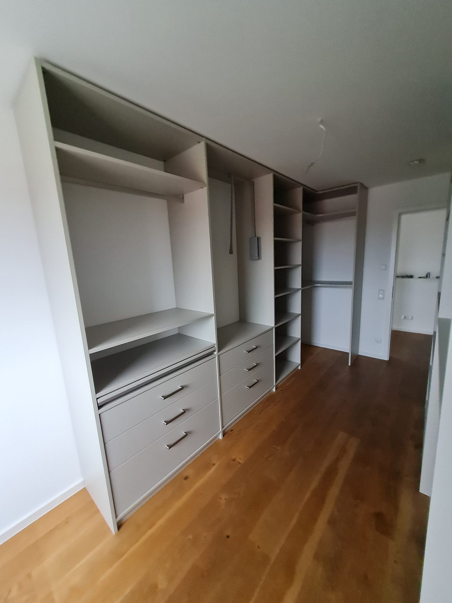 Ein Zimmer mit weißen Schränken und warmen Holzböden, das eine helle und einladende Atmosphäre schafft.